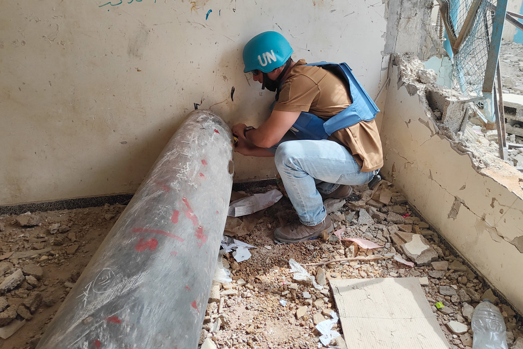 موظف من دائرة الأمم المتحدة للإجراءات المتعلقة بالألغام (أونماس) يفحص صاروخا غير منفجر في مدرسة في خان يونس. 